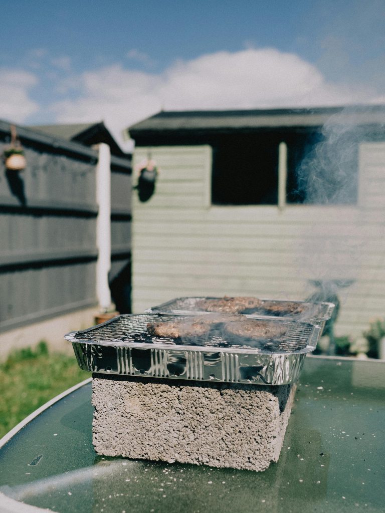 Un barbecue en métal fumant dans une arrière-cour avec une base en brique.