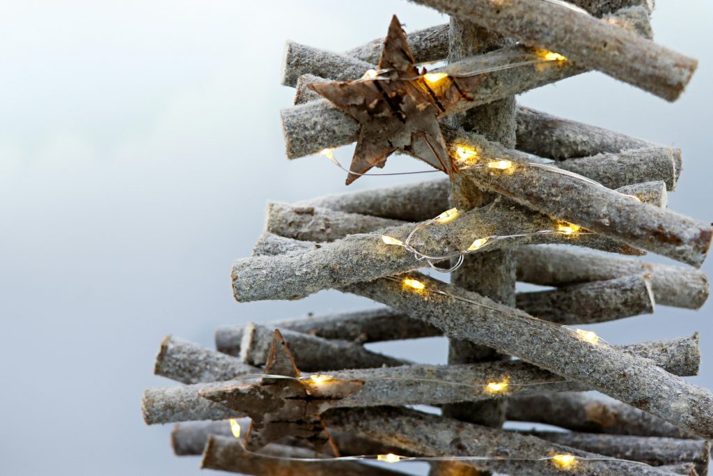 Un sapin de Noël en bois minimaliste et écologique décoré d'étoiles et de lumières.