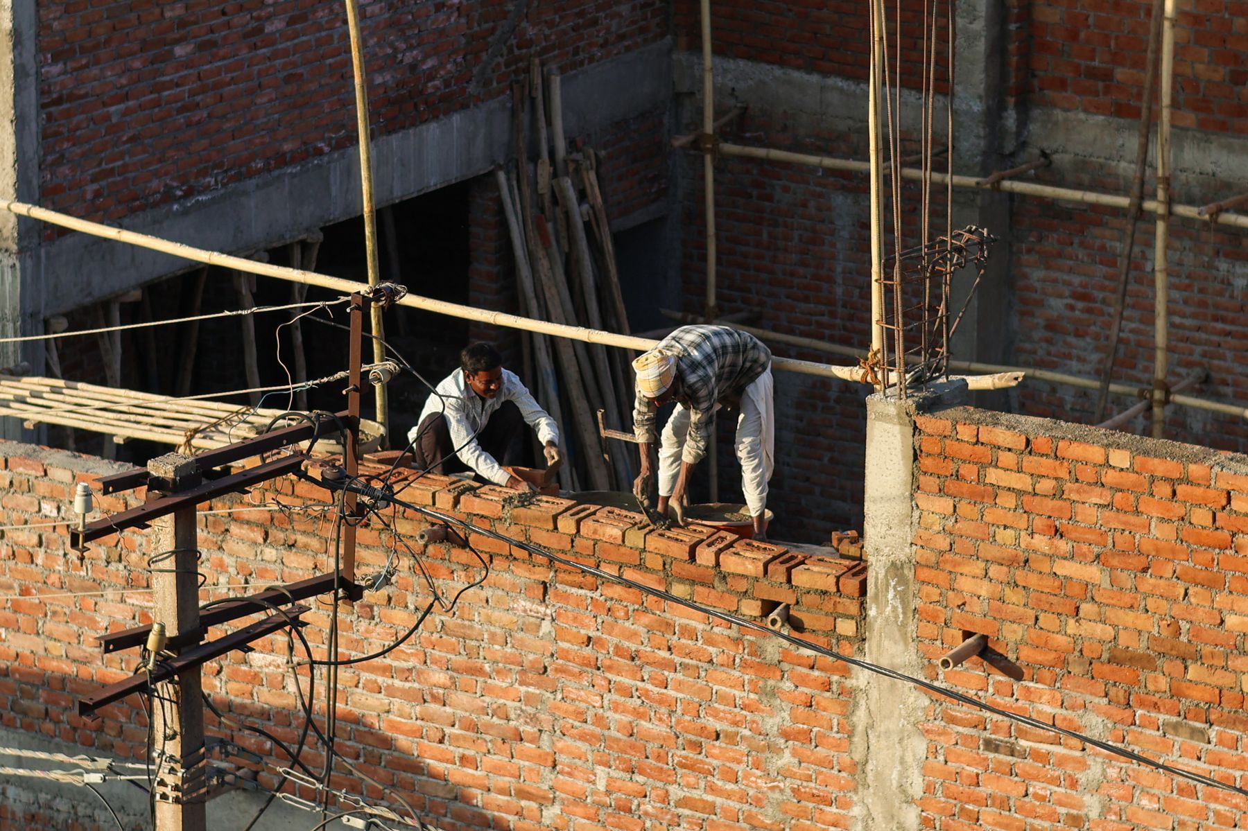 Deux ouvriers qui construisent un mur en briques